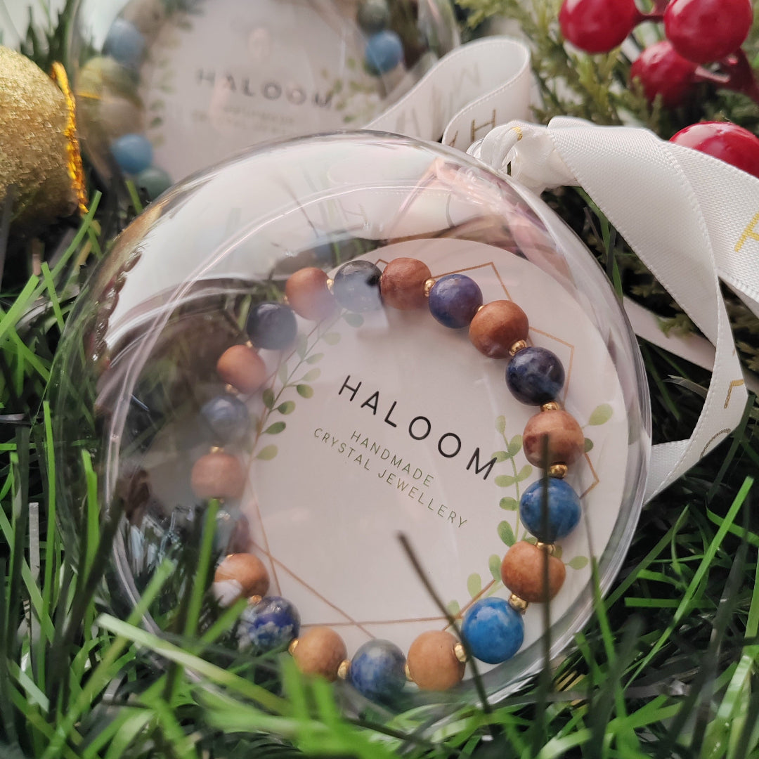 Crystal bracelet in a clear plastic packaging with 'HALOOM' branding on a grassy background.