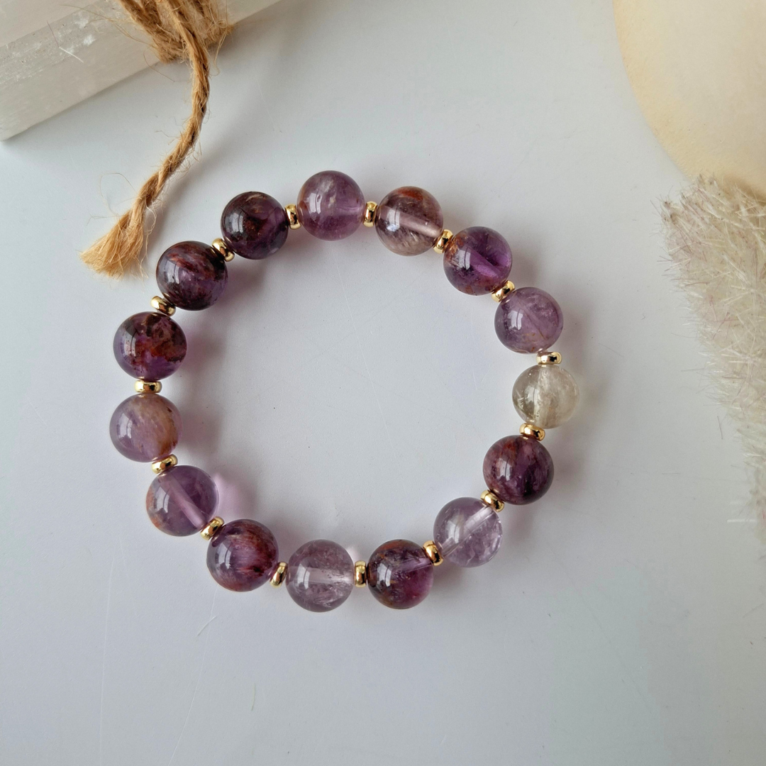 Beaded bracelet with purple and gold beads on a light background